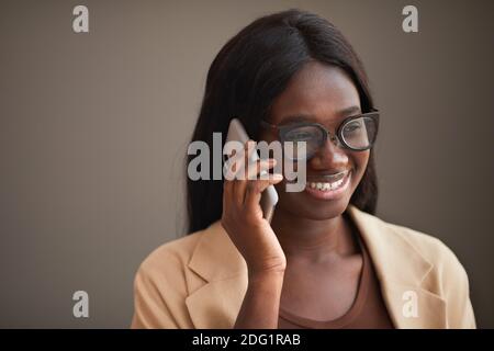 Kopf und Schultern Porträt der erfolgreichen afroamerikanischen Geschäftsfrau sprechen per Telefon im Büro und lächelnd, Kopierer Raum Stockfoto