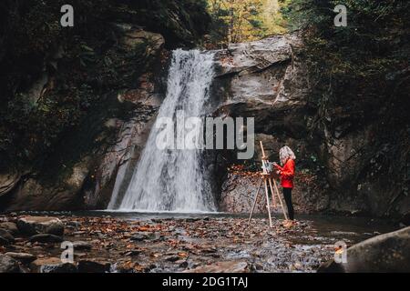 Malerin Künstlerin Malerei EIN Bild in der Nähe eines Wasserfalls Stockfoto