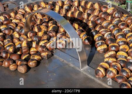 Kastanien (Castanea sativa) auf heißer Metallplatte geröstet, Street Food zum Verkauf Stockfoto