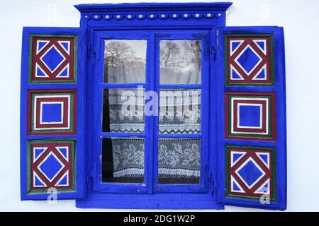 Das Dorfmuseum in Bukarest, Rumänien. Fenster eines Hauses aus dem 19. Jahrhundert aus Tulcea County mit hölzernen bemalten Fensterläden Stockfoto