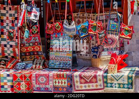 Gjirokaster Stadt, Albanien –2. August 2020: Magnete, handgemachte bunte gewebte Taschen, kleine Teppiche und Tischkleidung zum Verkauf im Outdoor-Souvenirshop. Stockfoto