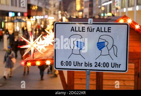 Leipzig, Deutschland. Dezember 2020. Passanten gehen durch die Fußgängerzone in der Grimmaische Straße in der Leipziger Innenstadt hinter einem Schild "Alle für alle" von "6:00 bis 24:00", das darauf hinweist, dass Masken obligatorisch sind. In keinem anderen Bundesland breitet sich die Corona-Pandemie derzeit so schnell aus wie in Sachsen. Daher sind jetzt strengere Maßnahmen in Kraft, einschließlich Ausstiegsbeschränkungen. Alle Weihnachtsmärkte und die traditionellen Bergparaden im Erzgebirge sind abgesagt. Quelle: Jan Woitas/dpa-Zentralbild/ZB/dpa/Alamy Live News Stockfoto