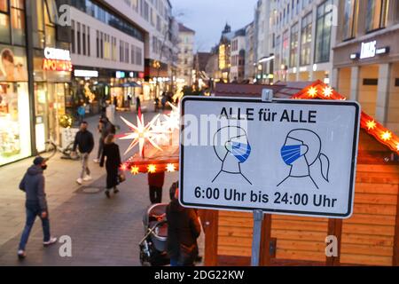 Leipzig, Deutschland. Dezember 2020. Passanten gehen durch die Fußgängerzone in der Grimmaische Straße in der Leipziger Innenstadt hinter einem Schild "Alle für alle" von "6:00 bis 24:00", das darauf hinweist, dass Masken obligatorisch sind. In keinem anderen Bundesland breitet sich die Corona-Pandemie derzeit so schnell aus wie in Sachsen. Daher sind jetzt strengere Maßnahmen in Kraft, einschließlich Ausstiegsbeschränkungen. Alle Weihnachtsmärkte und die traditionellen Bergparaden im Erzgebirge sind abgesagt. Quelle: Jan Woitas/dpa-Zentralbild/ZB/dpa/Alamy Live News Stockfoto