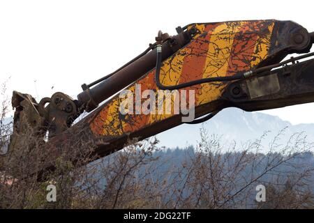 Ein alter schmutziger gelb-roter Baggerarm Stockfoto