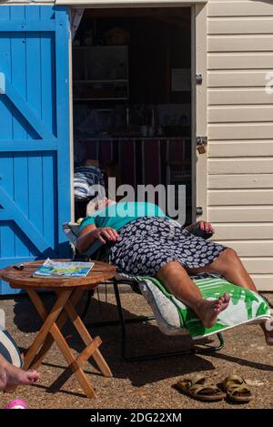 Genießen Sie die Sonne in einem Liegestuhl an der Küste von Kent in der Nähe von Margate, Thanet, England Stockfoto