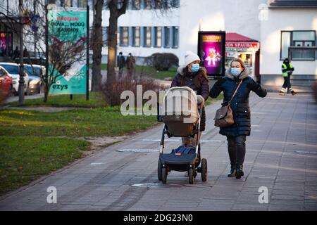 Mädchen mit Kinderwagen zu Fuß in der Stadt in der Nähe eines Geschäfts oder Einkaufszentrum während Covid oder Coronavirus Ausbruch, Weihnachten Hintergrund Stockfoto