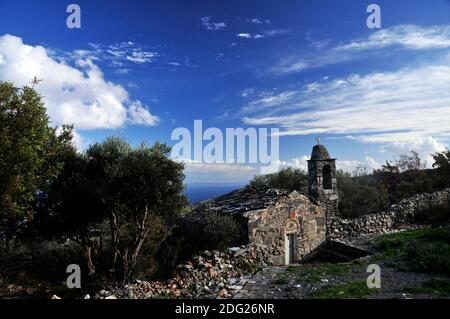 Steinkapelle in schöner Umgebung in Mani, Peloponnes, Griechenland. Olivenhain, blauer Himmel und schöne Wolkenformationen. Stockfoto