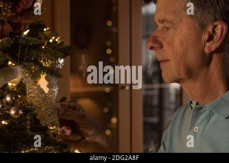 Älterer erwachsener Mann mit weihnachtsbaum, der nachdenklich und nachdenklich aussieht Als würde man sich an gute Zeiten in der Vergangenheit erinnern Stockfoto