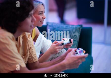 Lächelndes Paar hält Gamepads spielen Videospiel zu Hause. Junge Menschen verbringen Zeit zusammen während der Selbstisolation gegen Pandemie. Stockfoto