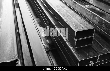 Stapel von gewalzten Metallprodukten, graue Stahlrohre mit rechteckigem Querschnitt, Nahaufnahme schwarz-weiß Foto mit selektivem Weichfokus Stockfoto