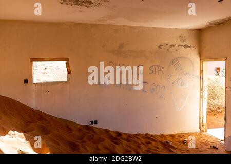 Vernachlässigtes Haus Interieur im Sand im Dorf Al Madam in Vereinigte Arabische Emirate begraben, mit gruseligen Inschrift: "Hall I stay or shall I go" auf der Stockfoto