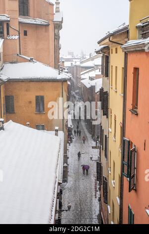 Schnee fällt auf bunte Häuser und Dächer und Straße in der Altstadt von Bologna, Italien Stockfoto