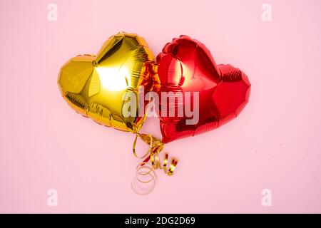 Zwei rote und goldene Herzen Folienballons obere Ansicht auf rosa Valentinstag Hintergrund. Stockfoto