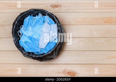 Abfalleimer mit Masken auf dem Boden, Ansicht von oben. Gebrauchte Masken. Einwegmasken im Abfalleimer. Medizinische Maske nach Gebrauch. Medizinischer Abfall. Verwendete Masken in einem Stockfoto