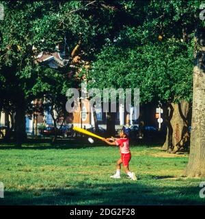 New York 1985, kleiner afroamerikanischer Junge, der Baseball spielt, schwingender Baseballschläger, Battery Park, Lower Manhattan, New York City, NY, NYC, USA, Stockfoto