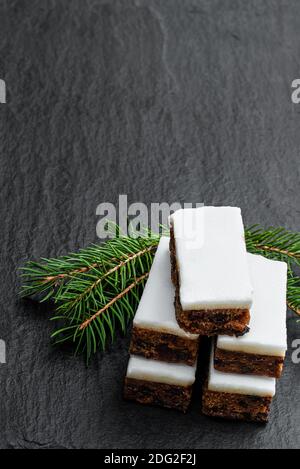 Obstkuchen Scheiben gekrönt mit Marzipan auf schwarzem Stein Hintergrund Stockfoto