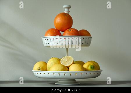 Schöne weiße metallische Obstschale mit frischen Zitronen und Orangen Stockfoto