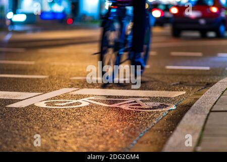 Biker fährt ab Fahrrad auf einer Straße in einer großen Stadt, vorbei an einem Fahrrad-Schild auf der Straße gedruckt Stockfoto