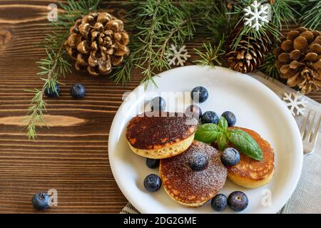Traditionelle japanische Pfannkuchen mit Heidelbeeren, garniert mit Zuckerpulver auf dem weißen Teller. Startseite Holzweihnachtstisch, Ansicht von oben. Stockfoto