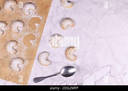 Traditionelle österreichische halbmondförmige weihnachtsplätzchen namens 'Vanillekipferl', ein Gebäck mit Nüssen und Puderzucker auf Backpapier mit Kopierfläche o Stockfoto