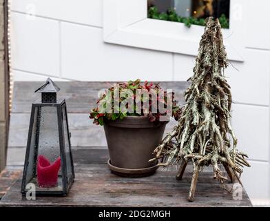 Weihnachten rote Beeren Pflanze in Topf, kreative Alternative Weihnachtsbaum aus Ästen und Straße Kerze Lampe auf Holztisch outsiade. Retro Stockfoto