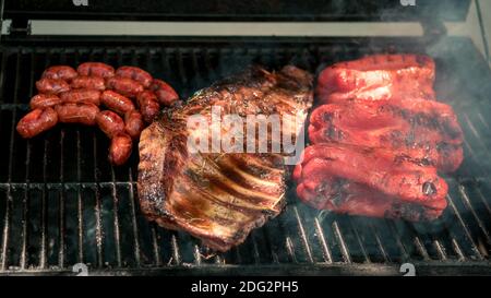 Kochen Schweinefleisch Rippchen mit roten Paprika auf BBQ Grill. Kochen Sie ein köstliches gegrilltes Fleisch. Essen gekocht mit Grillen Grill. Koch kocht Schweinefleisch im Hinterhof Stockfoto