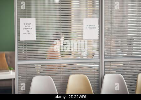 Hintergrundbild von Büroraum mit Schild Interview in Arbeit auf Glaswand und Silhouetten von Menschen, Raum kopieren Stockfoto