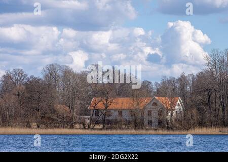 Alte verlassene Scheune mit rotem Dach am See Stockfoto