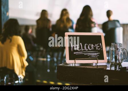 Willkommensschild hinter einer Gruppenbesprechung. Stockfoto