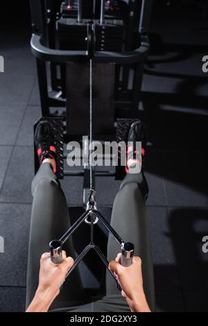 Teilansicht der Sportlerin beim Arbeiten am Rudergerät Unscharfer Hintergrund Stockfoto
