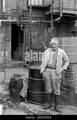 Großbritannien, London, Docklands, Isle of Dogs. Anfang 1974. Ein Mann, der in einem Fabrikhof in der Nähe von Coldharbour arbeitet. Stockfoto