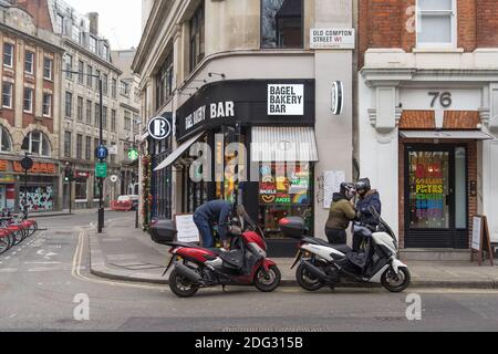 Moped-Zustellfahrer warten vor einer Bäckerei in der Old Compton Street, Soho. London Stockfoto