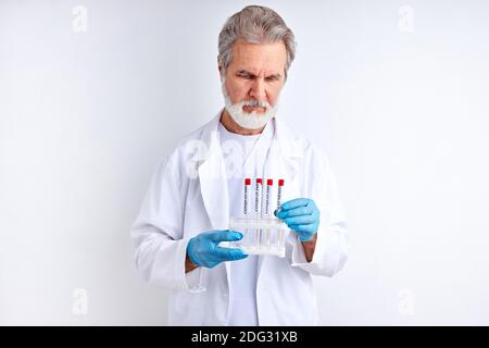 Doktor Wissenschaftler männlich hält Probenschlauch in der Hand, untersuchen Sie es. Arzt in Biohazard Schutzkleidung. Covid 19 Forschungslabor Stockfoto