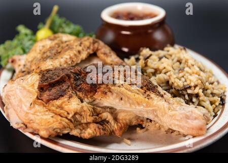 Frisch vom Grill halb gebratenes Hähnchen serviert mit allen bekannten gebackenen Kartoffeln und Reis Seiten. Stockfoto