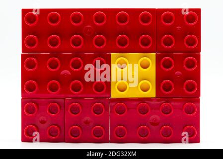 Gelber Lego-Baustein aus Kunststoff, umgeben von roten. Isolation und Diversity Konzept Stockfoto