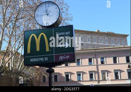 Ein Schild, das die Richtung eines neu eröffneten McDonald's Restaurants zeigt, ist am 4. Januar 2017 in Rom, Italien, mit den päpstlichen Appartements im Hintergrund in der Nähe des Vatikans zu sehen. Die amerikanische Fast-Food-Kette eröffnete ein Restaurant in einem Gebäude im Besitz des Vatikans, trotz des Protests eines Komitees zum Schutz von Borgo, dem historischen Viertel rund um den Vatikan, in dem viele Kardinäle leben. Trotz einer sehr öffentlichen Schlacht von Einheimischen und religiösen Beamten, um die Fast-Food-Kette aus dem päpstlichen Hauptsitz zu halten, öffnete eine Filiale der Golden Arches Kette Restaurant für Geschäfte nur wenige Meter von Saint PE entfernt Stockfoto