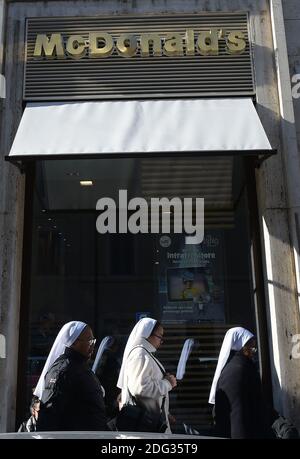 Nonnen gehen am 4. Januar 2017 in Rom, Italien, an einem neu eröffneten McDonald's-Restaurant in der Nähe des Vatikans vorbei. Die amerikanische Fast-Food-Kette eröffnete ein Restaurant in einem Gebäude im Besitz des Vatikans, trotz des Protests eines Komitees zum Schutz von Borgo, dem historischen Viertel rund um den Vatikan, in dem viele Kardinäle leben. Trotz einer sehr öffentlichen Schlacht von Einheimischen und religiösen Beamten, um die Fast-Food-Kette aus dem päpstlichen Hauptsitz zu halten, öffnete eine Filiale der Golden Arches Kette Restaurant für Geschäfte nur wenige Meter vom Petersplatz entfernt. Einige Kardinäle beschwerten sich darüber, dass sie vorher nicht konsultiert wurden Stockfoto