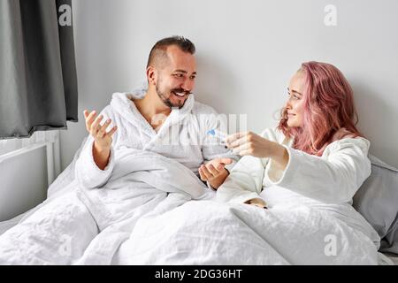 Mann glücklich reagieren auf Test der Schwangerschaft, freudiges Paar, das Ergebnisse eines Schwangerschaftstests zu Hause auf dem Bett liegend herausfindet Stockfoto