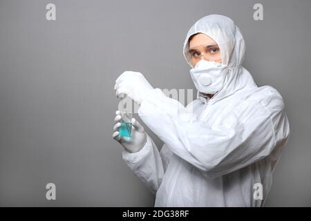 Covid19-Impfstoff in den Händen der Ärzte. Arzt in Schutzanzug, biologische Gefahr, medizinische Maske Handschuhe auf grauem Hintergrund. Coronavirus-Impfstoff Stockfoto