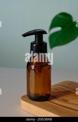 Klare Amber Glas Pumpe Flasche Mockup mit tropischen grünen Blatt. Spender Verpackungsdesign für natürliche Bio-Kosmetik. Stockfoto