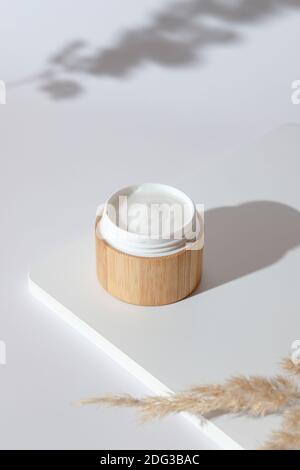 Feuchtigkeitsspendende Creme für die Hände in umweltfreundlichen Bambus-Glas und trockene Blumen auf weißem Hintergrund. Natürliches organisches kosmetisches Produkt Stockfoto