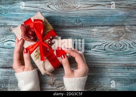 Geschenkbox in den Händen einer Frau auf einem Holzhintergrund. Stockfoto