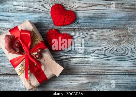 Zwei rote Herzen und ein Geschenk auf einem hölzernen Hintergrund. Stockfoto