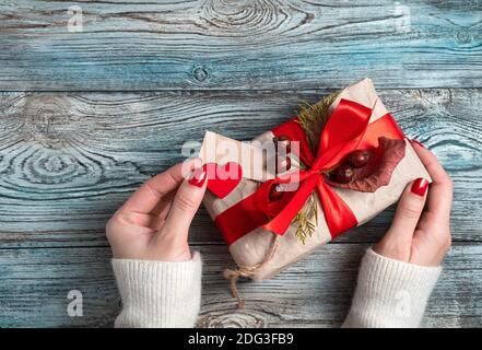 Damenhänden schmücken eine Geschenkbox auf einem Holzhintergrund. Stockfoto