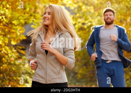 Paar laufen auf Herbst Waldweg, junge kaukasische fit Mann und Frau wärmen sich im Freien, genießen Joggen Stockfoto