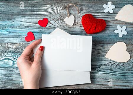 Eine Frau in der Hand hält einen leeren Brief auf einem romantischen Hintergrund. Stockfoto