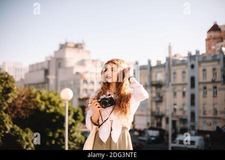 Nachdenkliche junge Frau, die Kamera hält, während sie in der Stadt steht Sommer Stockfoto