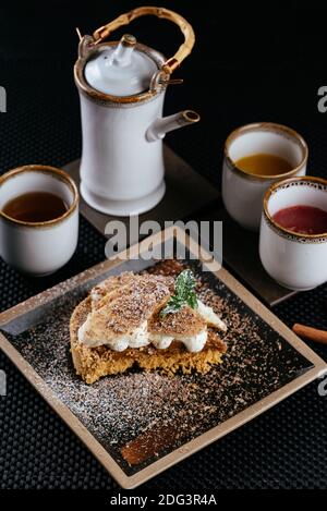 Verschiedene Desserts mit Tee auf schwarzem Hintergrund Stockfoto