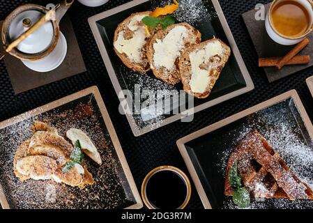 Verschiedene Desserts mit Tee auf schwarzem Hintergrund Stockfoto
