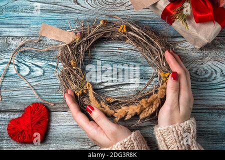 Ein Kranz in den Händen einer Frau auf einem romantischen Hintergrund. Stockfoto